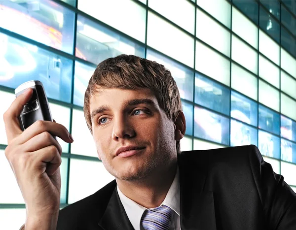 Молодой бизнесмен с мобильным телефоном на абстрактном фоне — стоковое фото