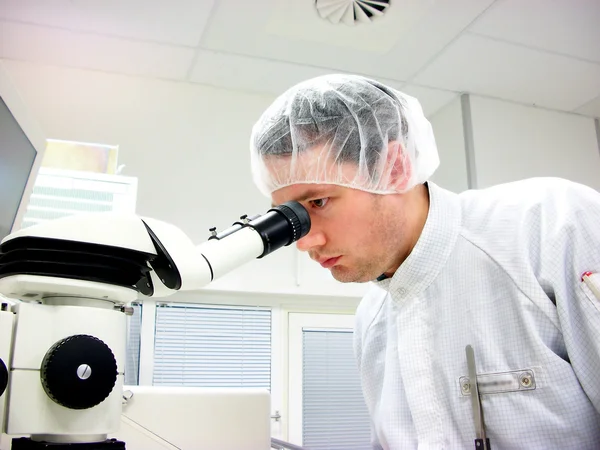 The men looks in stereomicroscope eyepieces — Stock Photo, Image