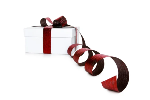 Caja blanca atada con un lazo de cinta de satén rojo — Foto de Stock