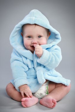 Charming baby boy in a blue bathrobe with a hood clipart