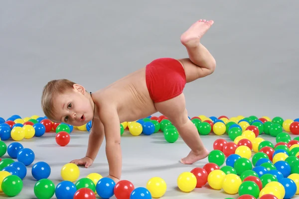 Criança está brincando com bolas coloridas — Fotografia de Stock