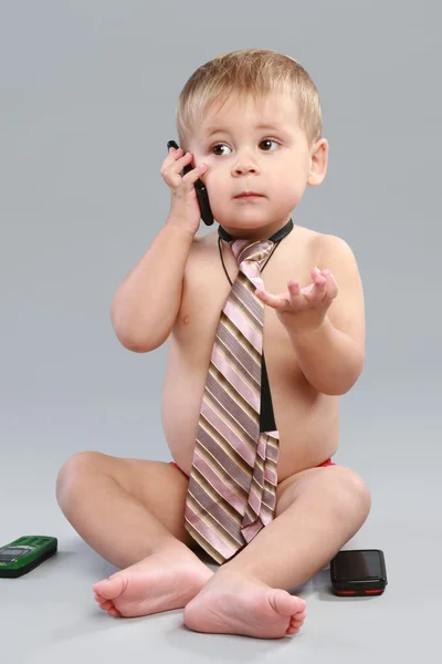 在领带的小男孩讲话的灰色背景上的移动电话 — 图库照片