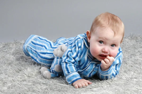Adorabile bambino sdraiato su uno sfondo grigio — Foto Stock