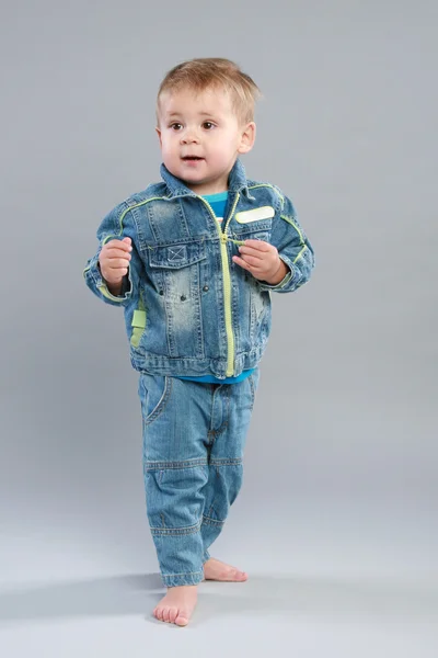 可爱的小男孩 在灰色的背景上牛仔裤 — 图库照片