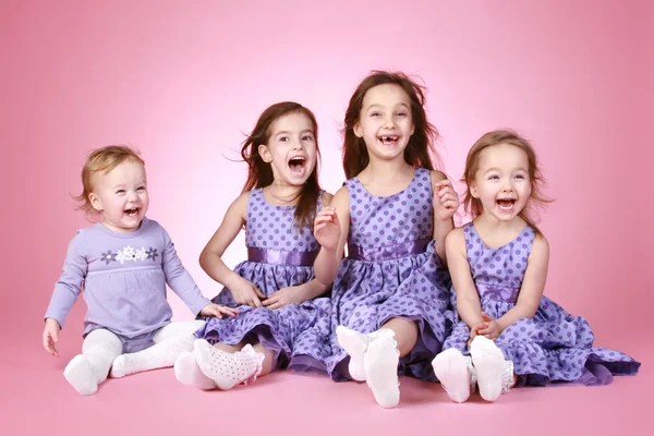 Vier glückliche junge Mädchen in violettem Kleid lachen — Stockfoto