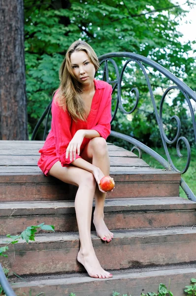 Belle femme dans une robe rouge assise sur le pont — Photo
