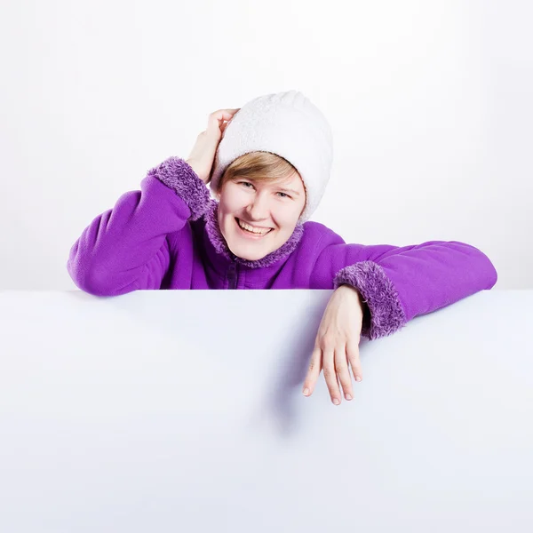 暖かいキャップと空のホワイト ボードを示すセーターで若い女性 — ストック写真