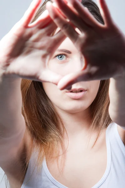 Portrait of eyes looking through fingers frame — Stock Photo, Image