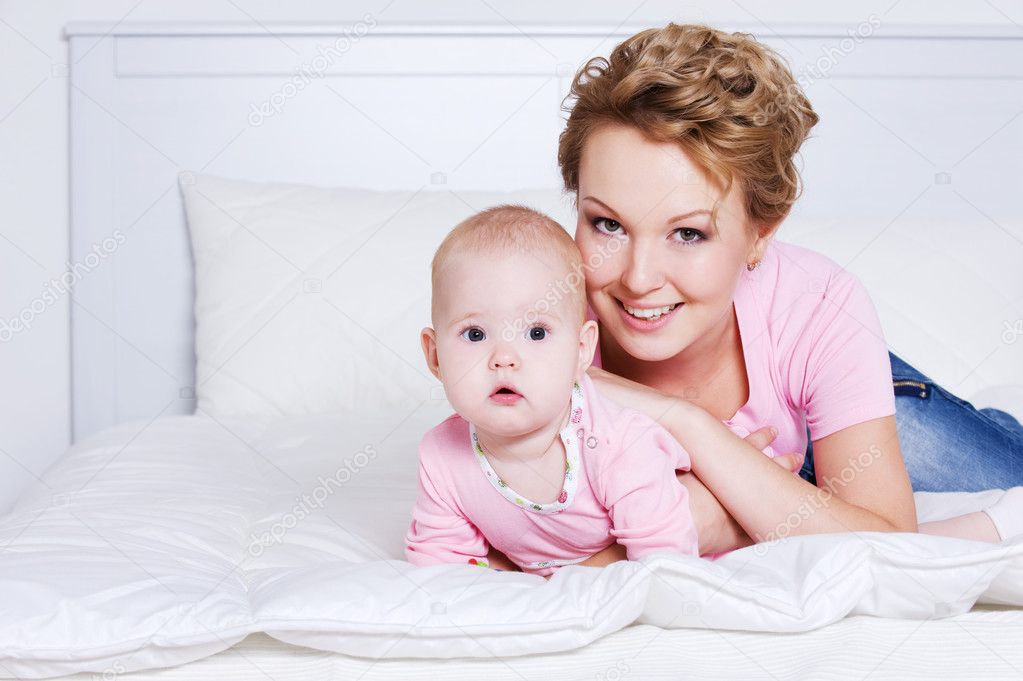 Beautiful mother lying with her baby on the bed — Stock Photo ...