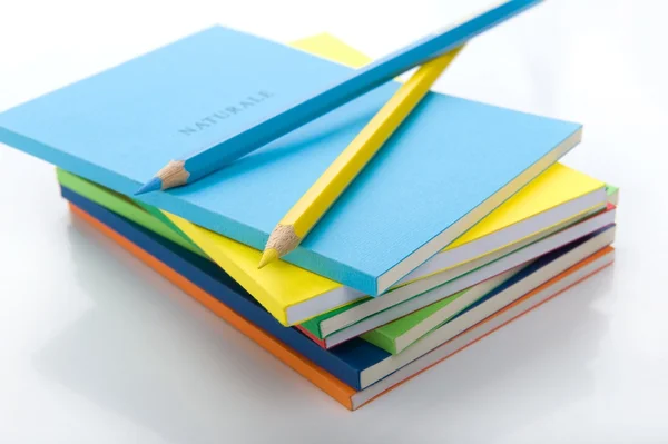 Dvě barevné tužky pod Stoh knih — Stock fotografie