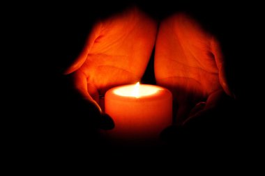 Glowing warmth in the hands. Hands carry a burning candle - Religion concept clipart