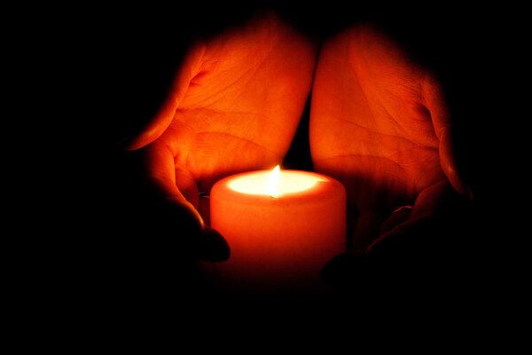 Glowing warmth in the hands. Hands carry a burning candle - Religion concept