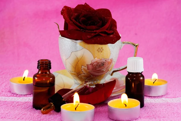Τριαντάφυλλο Ένα Φλιτζάνι Αναμμένα Κεριά Και Αρωματικά Έλαια Ροζ Φόντο — Φωτογραφία Αρχείου