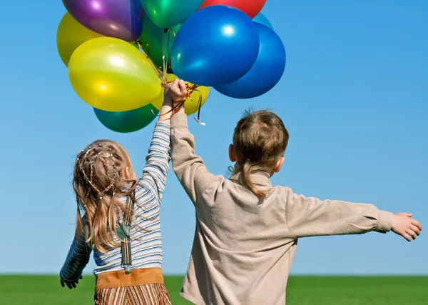 快乐妹妹和弟弟与气球行走在春天字段 — 图库照片