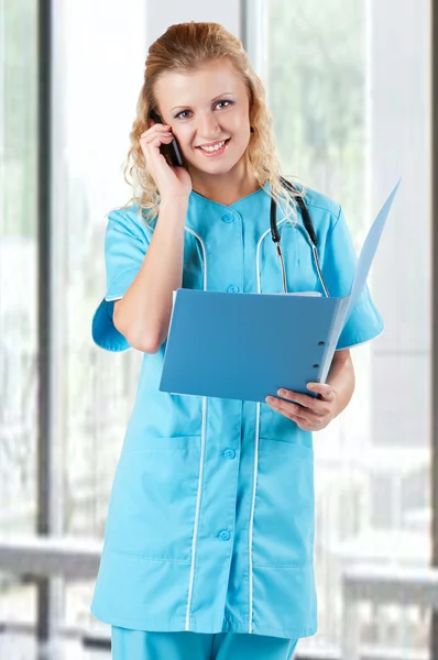美しい若い医者病院で携帯電話を保持するファイル フォルダー — ストック写真