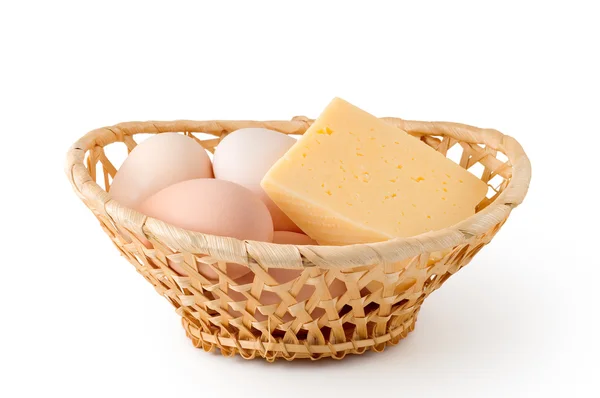 Huevos y queso yacen en una cesta tejida — Foto de Stock