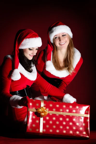 Duas mulher fantasiada de Papai Noel, abrindo o presente de Natal. — Fotografia de Stock