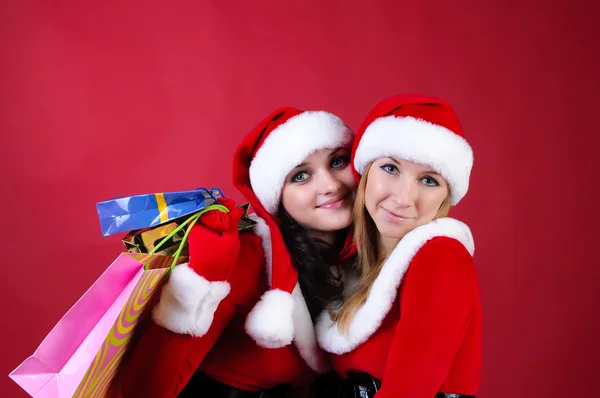 Dos mujeres en vestidos de Papá Noel, con bolsas de compras . —  Fotos de Stock