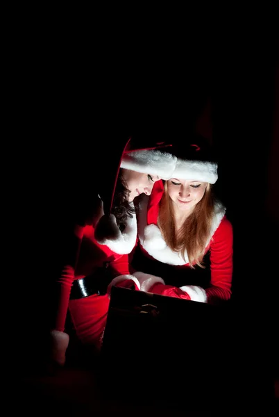 Dos mujeres en traje de santa abriendo el regalo de Navidad. — Foto de Stock