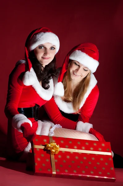 Two woman in Santa costume opening christmas gift. — Stock Photo, Image