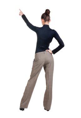 Beautiful young woman pointing at wall. Rear view. clipart