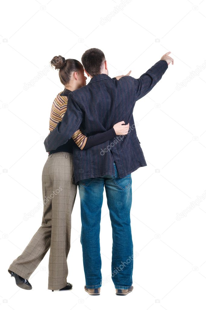 Young couple pointing at wall. Rear view.