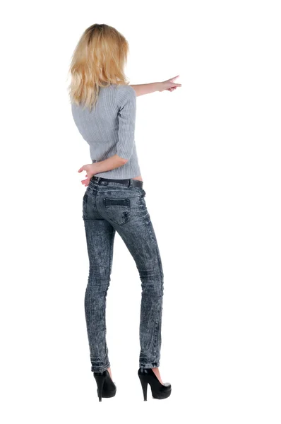 Beautiful young woman pointing at wall. Rear view. — Stock Photo, Image
