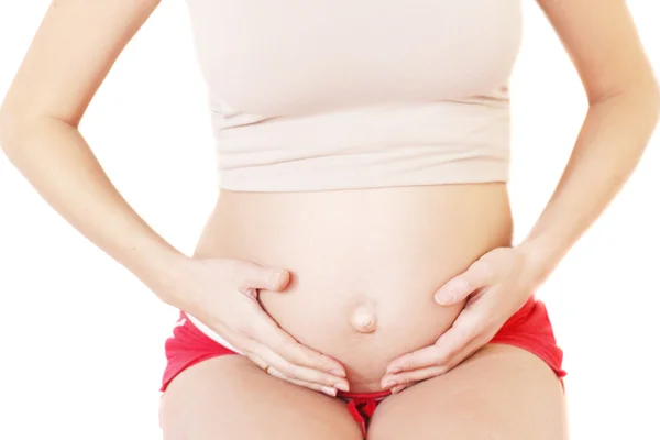 Terhes nő fogdossa a hasát Jogdíjmentes Stock Képek