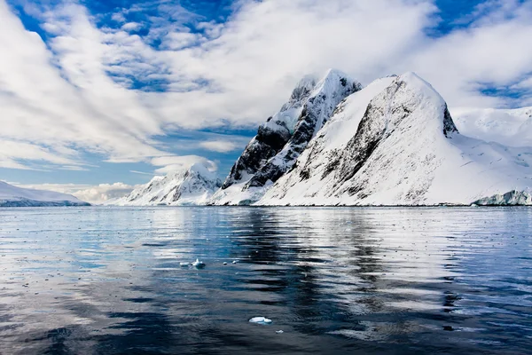 南極の青い空を背景の美しい雪をかぶった山々 ストック写真