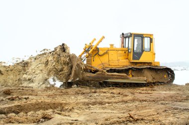 A yellow bulldozer working in the winter clipart