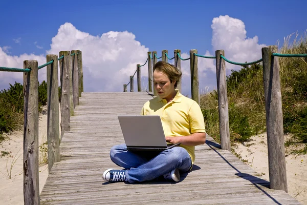 在海滩上与计算机工作的年轻人 — 图库照片