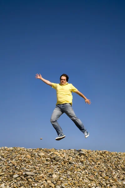 若い男のバック グラウンドとして空とビーチにジャンプします — ストック写真