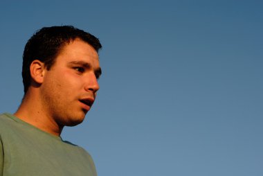 Retrato de hombre joven con el cielo como fondo en la luz del atardecer