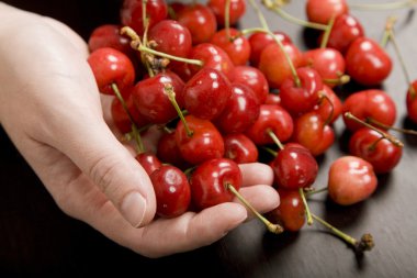 bir masada bir kadın elinde birçok kiraz