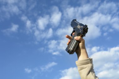 gun in a child hand with clouds in the sky clipart