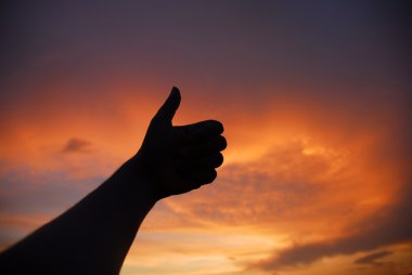 Thumbs up human hand in the sunset colors clipart