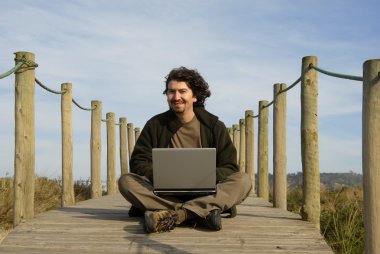 genç adam sahilde bilgisayar ile çalışma