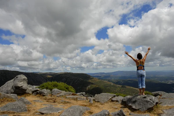 stock image young woman with arms wide open at the mountains