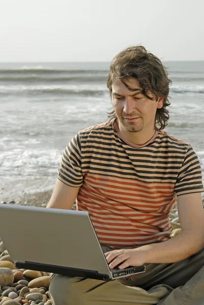 年轻男子在沙滩上用的笔记本电脑 — 图库照片