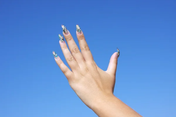 Krásná žena ruku na pozadí modré oblohy — Stock fotografie