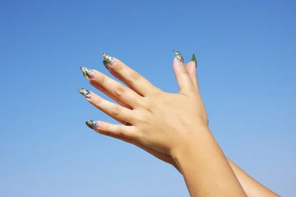 Mooie vrouw handen op een achtergrond blauwe hemel — Stockfoto
