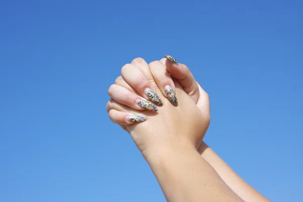 Belle mani di donna su uno sfondo cielo blu — Foto Stock
