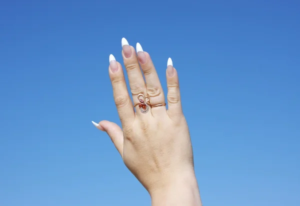 Рука женщины на фоне голубого неба — стоковое фото