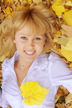 bir sonbahar Park sarı yapraklar üzerinde çekici genç bir kadın yatıyor