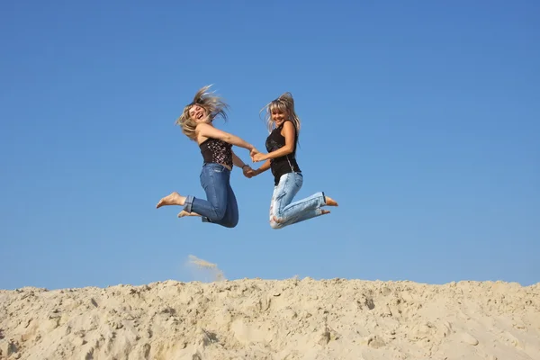 Two beautiful women in summer jump on a sand-pit — Stock Photo, Image