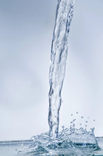 Водный поток с брызгами на голубом — стоковое фото