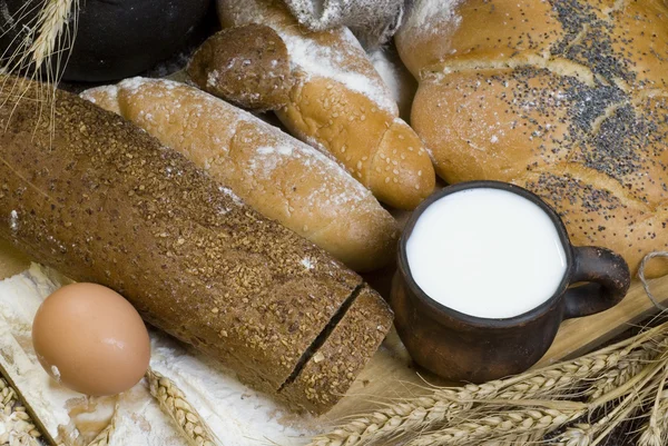 Pan, harina, cereales, huevo y una taza de leche . —  Fotos de Stock