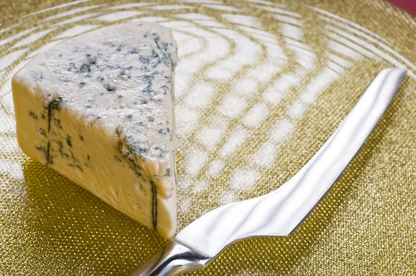 Синий сыр и нож на тарелке — стоковое фото