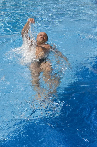 Mann schwimmt in einem Pool Stockbild
