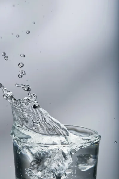 Fresh water splashing out of a glass with ice — Stock Photo, Image
